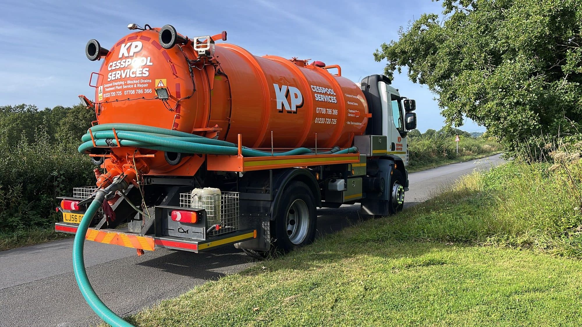KP Cesspool Services orange vacuum tanker parked on a Kent country lane with its suction hose run out
